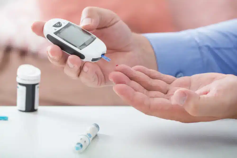 Osoba drží glukometr a připravuje se na měření hladiny cukru v krvi, což je důležitý krok pro správu diabetes.