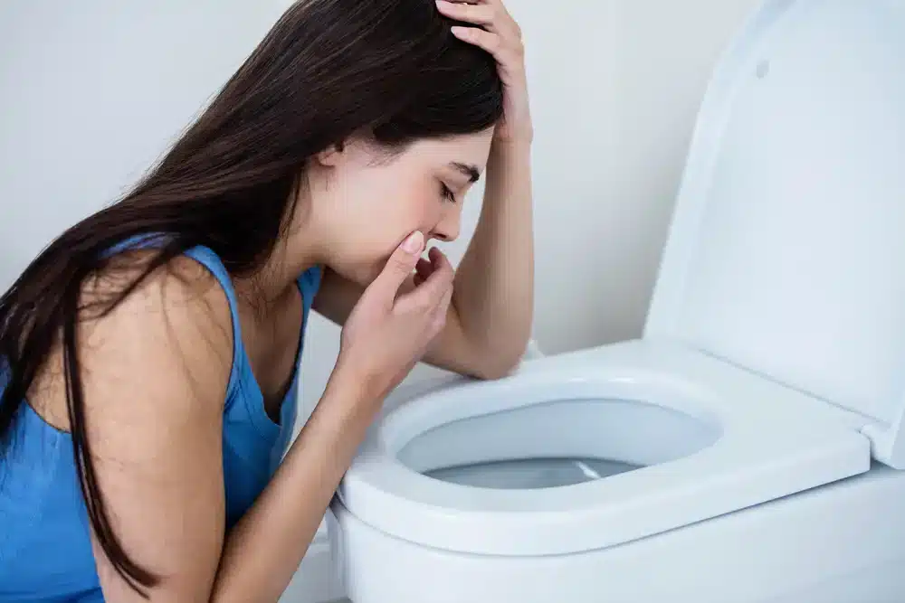 Žena se sklání nad toaletou, což je typický znak zvracení, jež je důležité rychle a efektivně zvládnout.