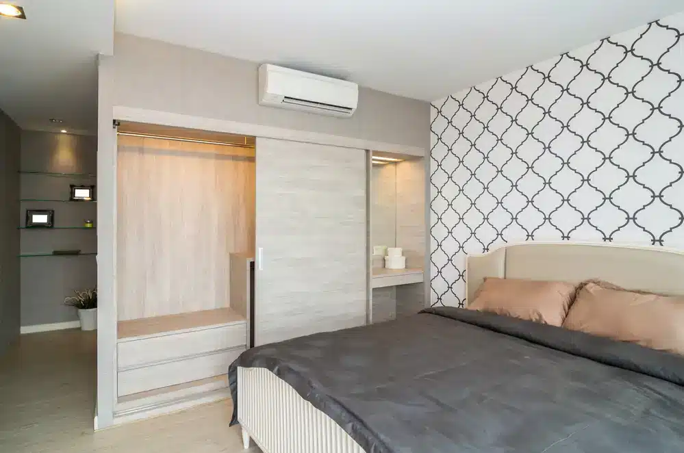Moderní ložnice s výrazným vzorovaným tapetováním a vestavěnými úložnými prostory, vhodná pro maximální využití prostoru v malém bytě.