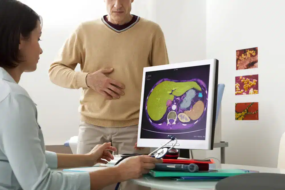 Lékařka ukazuje pacientovi CT snímek jater s možnými metastázami.